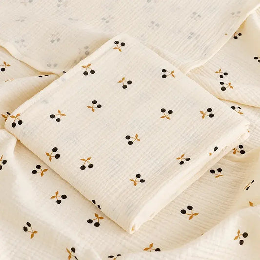 couverture d’emmaillotage bébé motif cerises en tissu doux pliée sur fond assorti