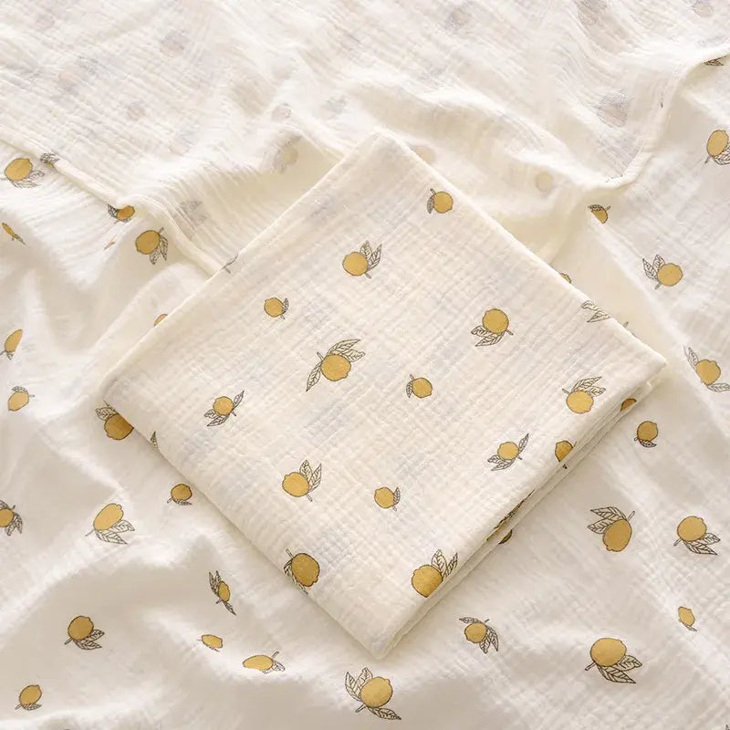 couverture d’emmaillotage bébé motif citrons en tissu doux pliée sur fond assorti