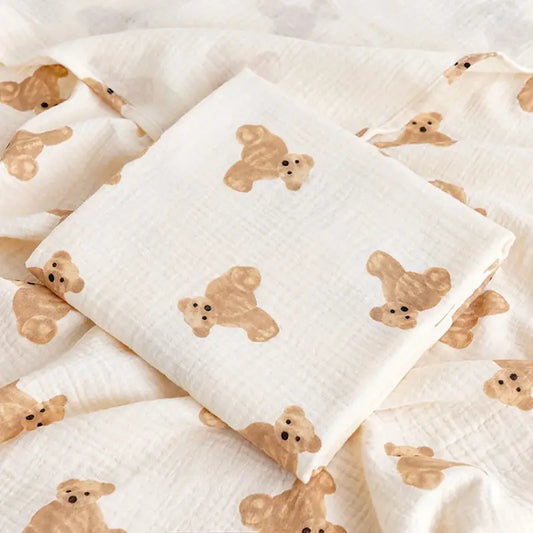 couverture d’emmaillotage bébé motif ourson en tissu doux pliée sur fond assorti