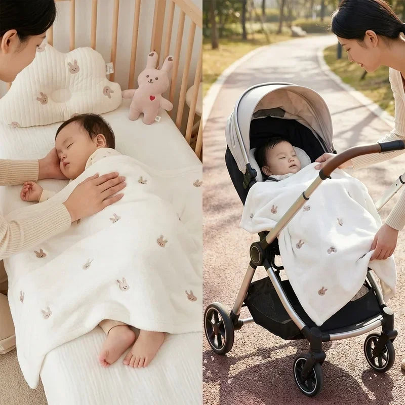 Maman couvrant son bébé avec une couverture polaire blanche motif lapins, utilisation polyvalente à la maison dans le berceau et en poussette à l’extérieur, texture douce et chaude adaptée à l’hiver.