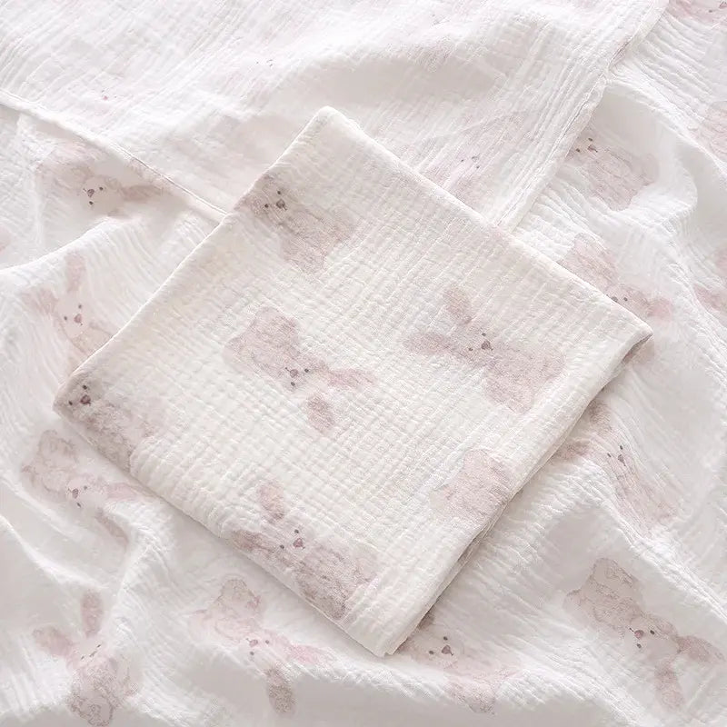 couverture d’emmaillotage bébé motif lapins en tissu doux pliée sur fond assorti