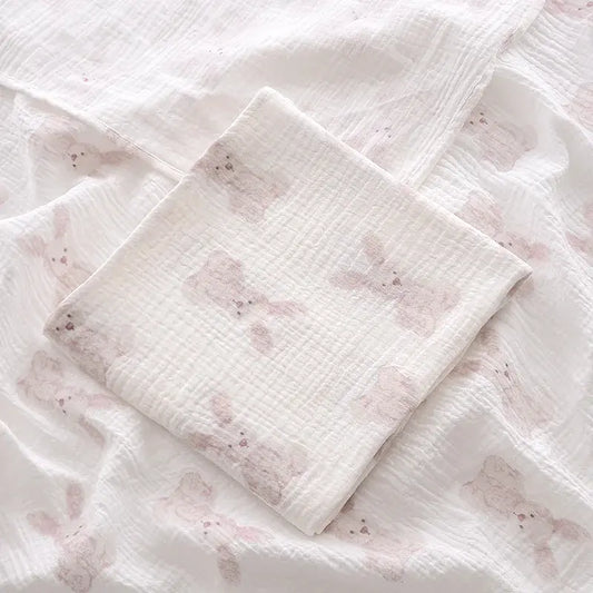 couverture d’emmaillotage bébé motif lapins en tissu doux pliée sur fond assorti