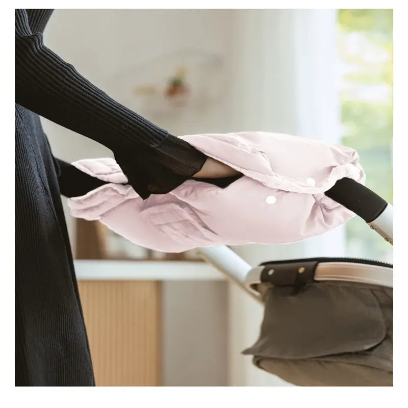 Gants de poussette hiver ultra chauds rose fixés sur une poussette pour protéger les mains du froid pendant les promenades hivernales avec bébé.