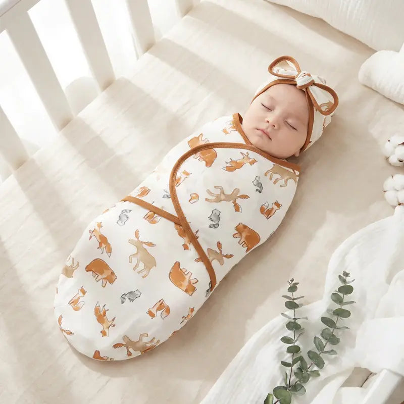 Bébé endormi dans un nid d’ange léger blanc motif animaux de la foret spécial été, installé dans un berceau en bois clair, ambiance douce et lumineuse.