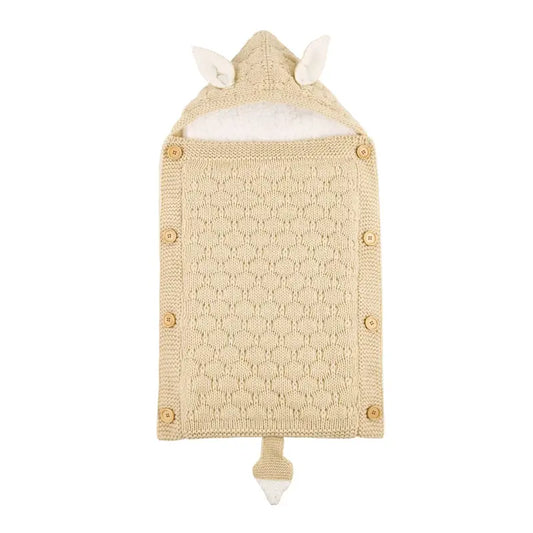 Nid d’ange bébé tricot beige avec capuche à oreilles, boutons en bois et maille texturée, présenté à plat sur fond clair.