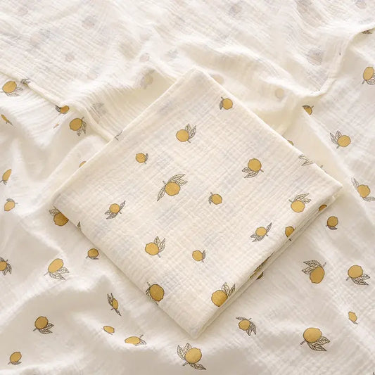 couverture d’emmaillotage bébé motif citrons en tissu doux pliée sur fond assorti