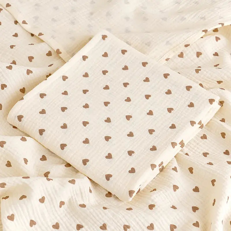 couverture d’emmaillotage bébé motif cœurs en tissu doux pliée sur fond assorti
